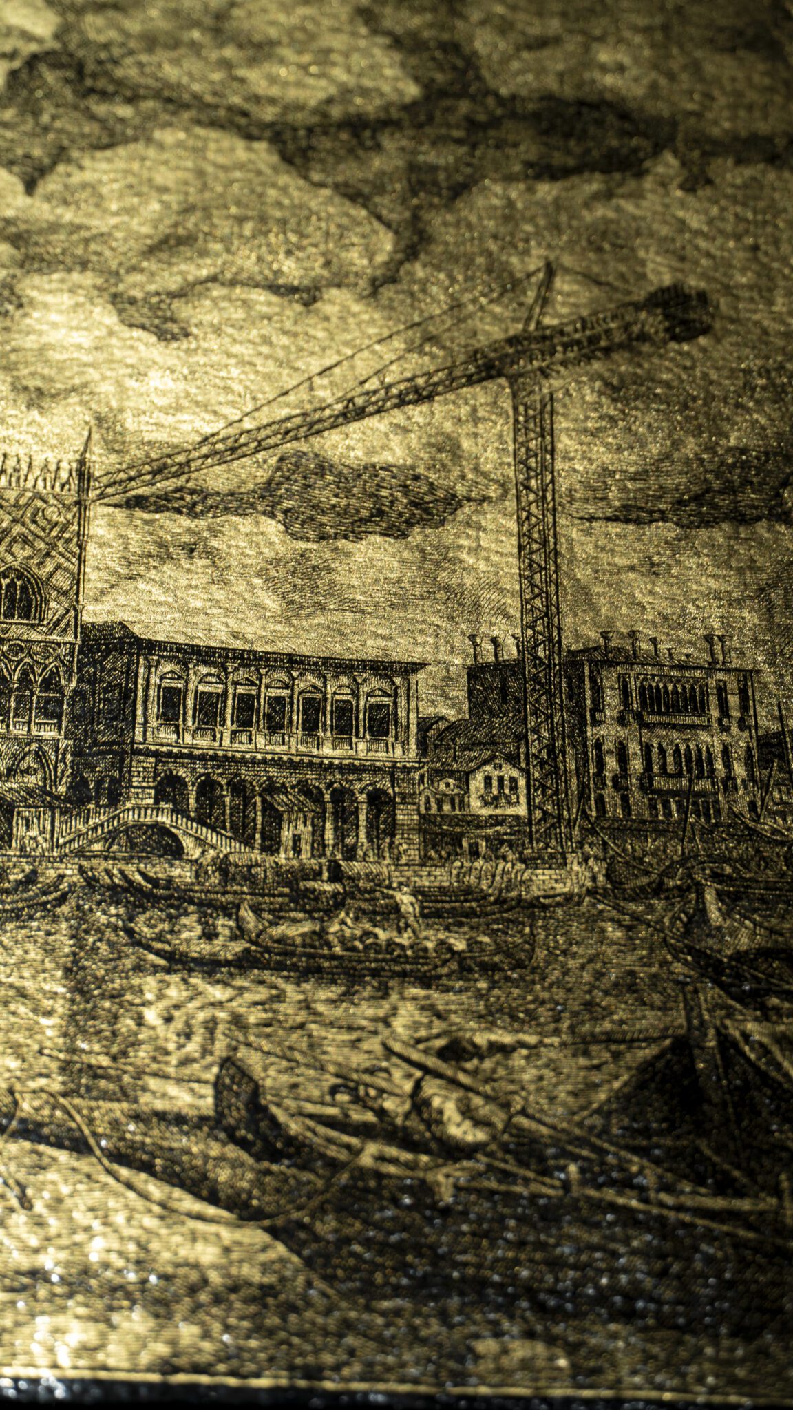 Detail of the artwork “An Icon of Venice”: waterfront façades and a contemporary crane engraved on gold leaf, with boats in the foreground.