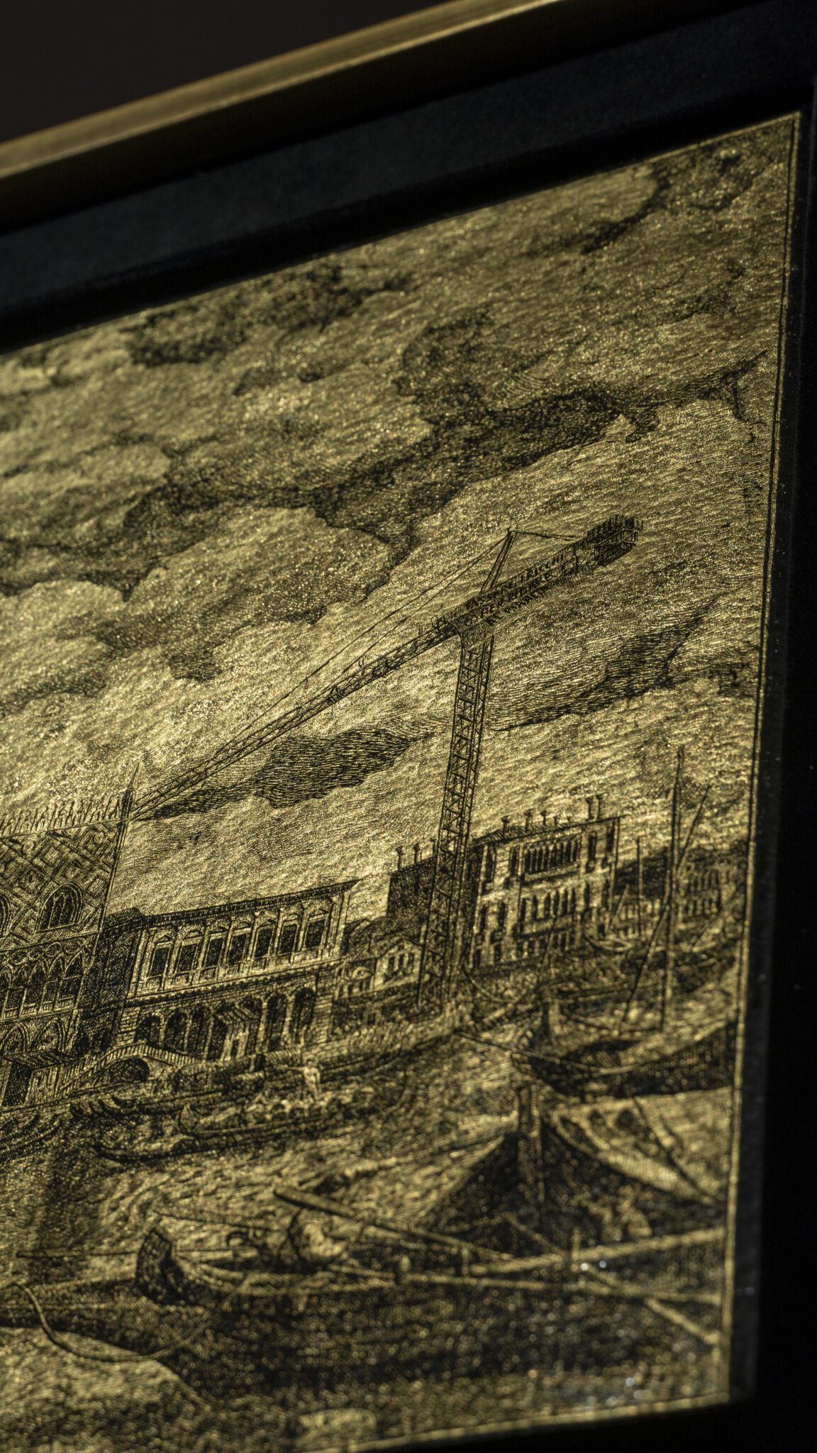 Detail of the artwork “An Icon of Venice”: waterfront facades and a contemporary crane engraved on gold leaf, with boats in the foreground.